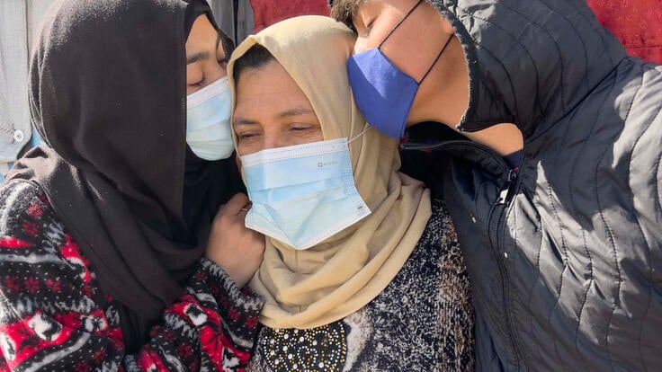 Lina standing to the left of her mother, with her brother Ahmad at the right. Both are kissing their mom on the head